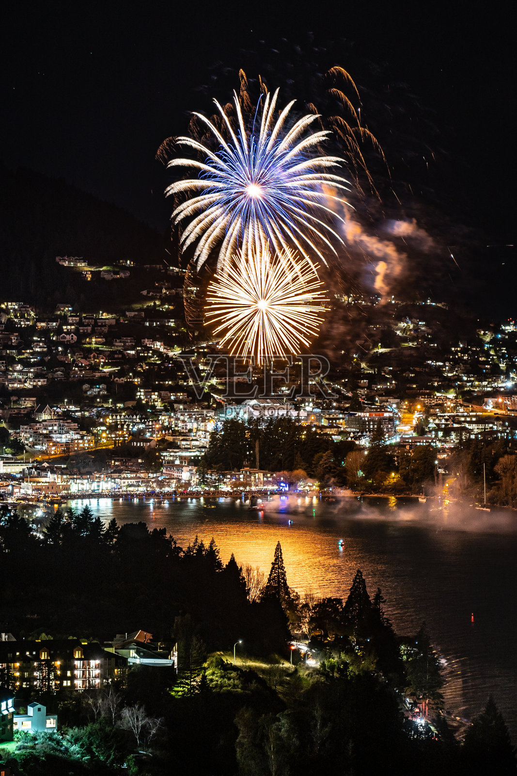 在冬季节日期间，皇后镇有精彩的烟火表演。以城市为背景的湖上灯光照片摄影图片