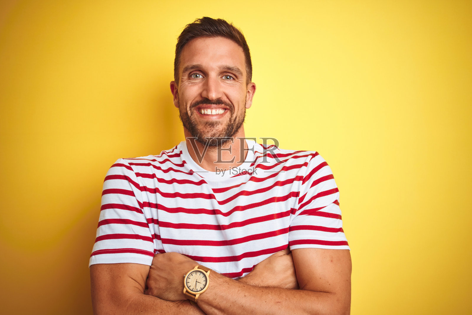 穿着红色条纹T恤的年轻帅气男子，面带微笑，双手交叉，自信积极照片摄影图片