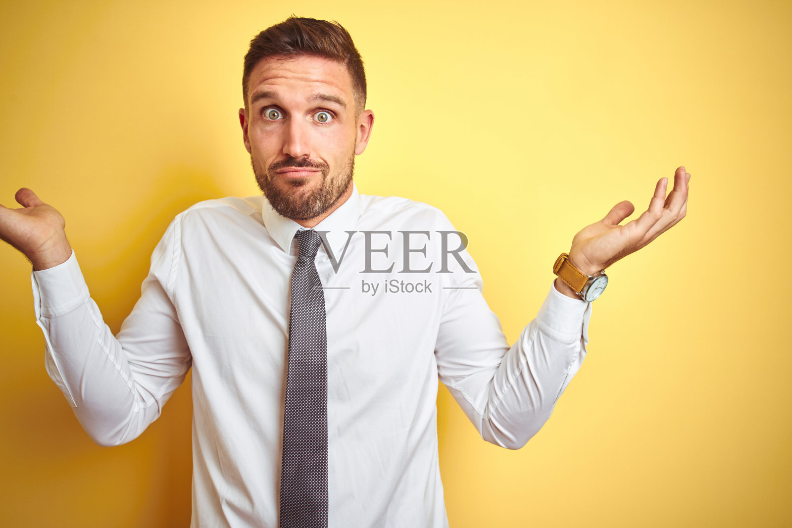 穿着白色衬衫的年轻商务男士，双手抬起，困惑不解照片摄影图片