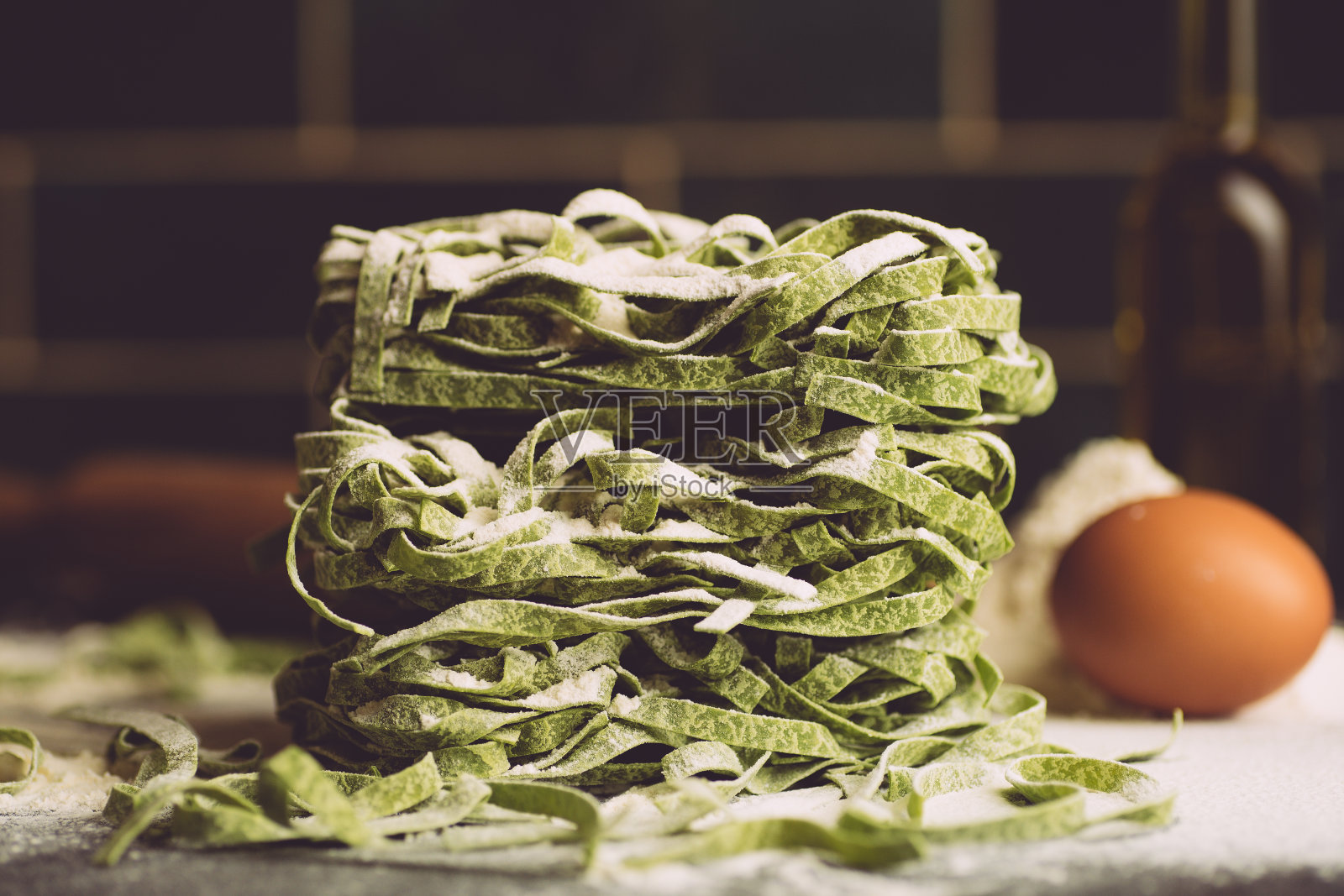意大利面食的背景。纯素食意大利面食与新鲜的菠菜(菠菜宽面条阿尔弗雷多面食)在一个黑暗的背景。旧厨房背景。本空间照片摄影图片