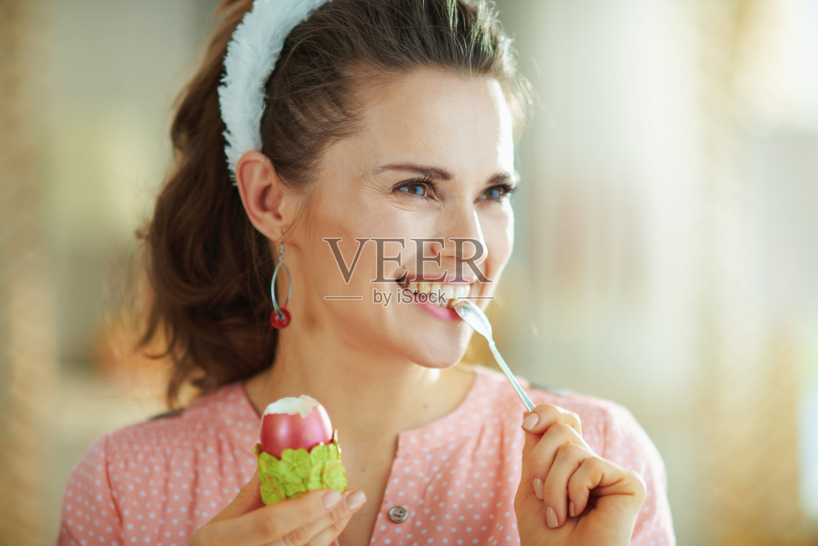 女人在阳光明媚的春日里，在现代化的家中用勺子吃鸡蛋照片摄影图片