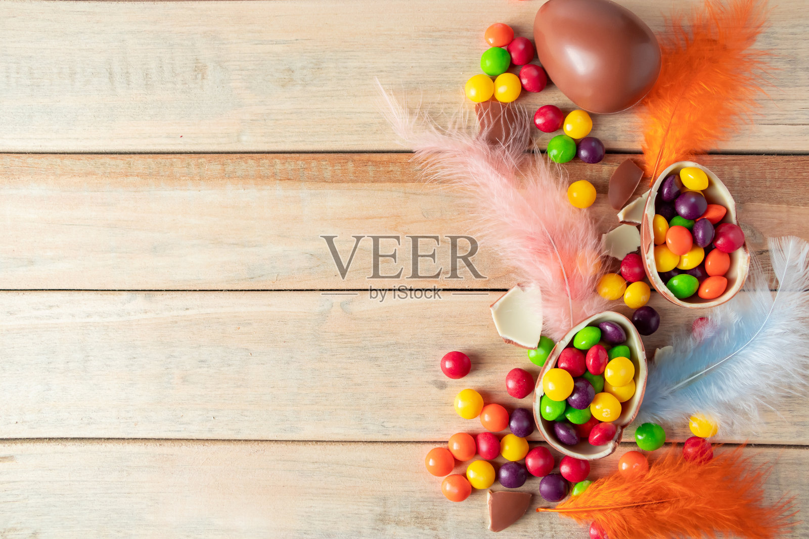 用巧克力做成的复活节彩蛋和精致的羽毛在一个明亮的背景上。照片摄影图片