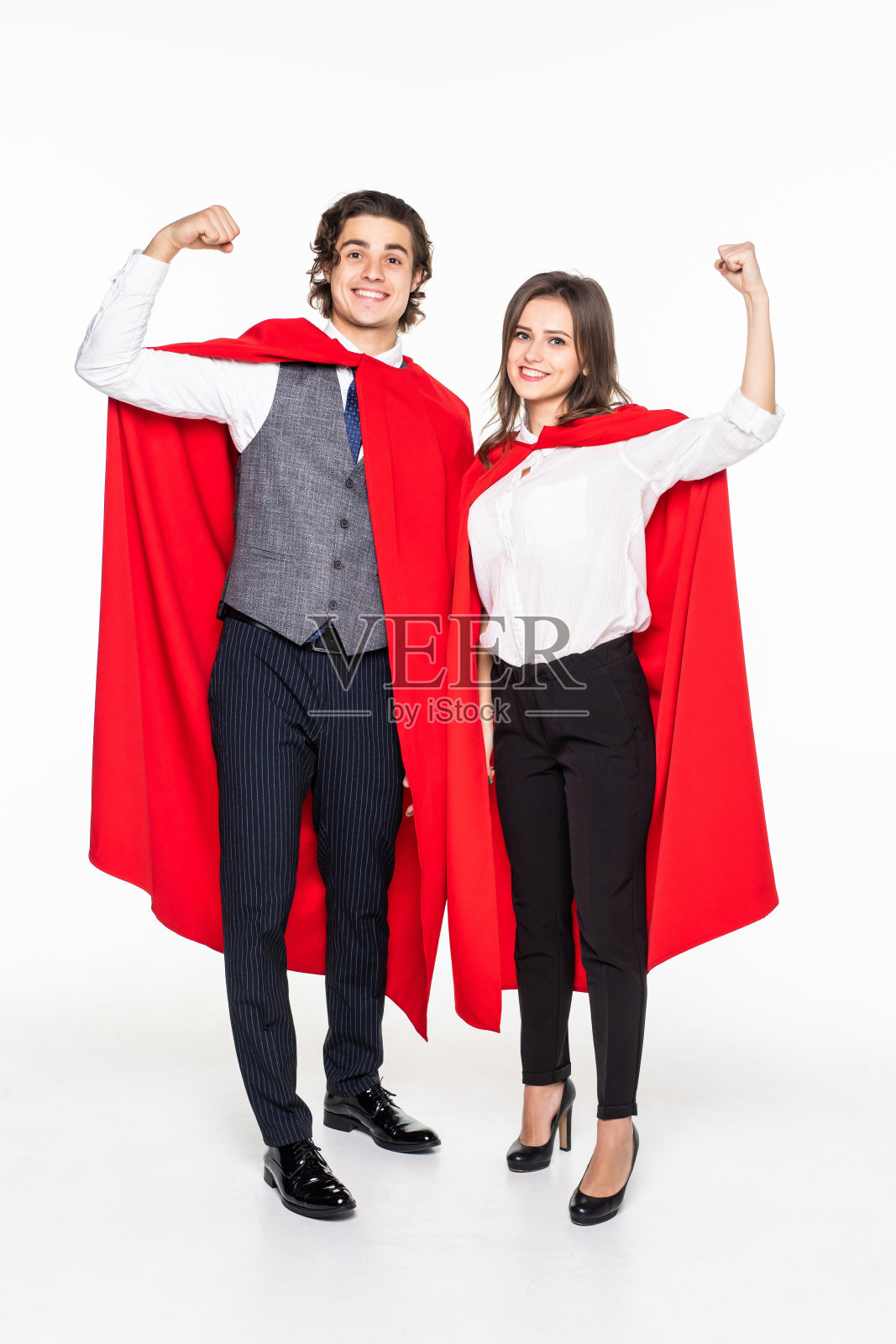 身穿红色斗篷、交叉双臂、看着镜头的年轻情侣，白色背景照片摄影图片