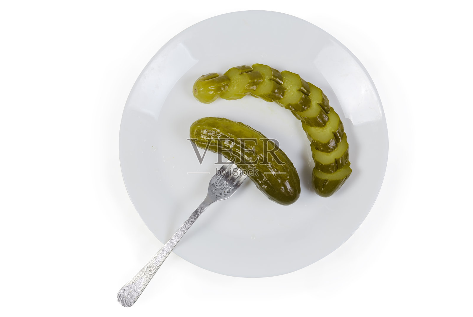用叉子刺穿的黄瓜罐头，白盘上的黄瓜片照片摄影图片