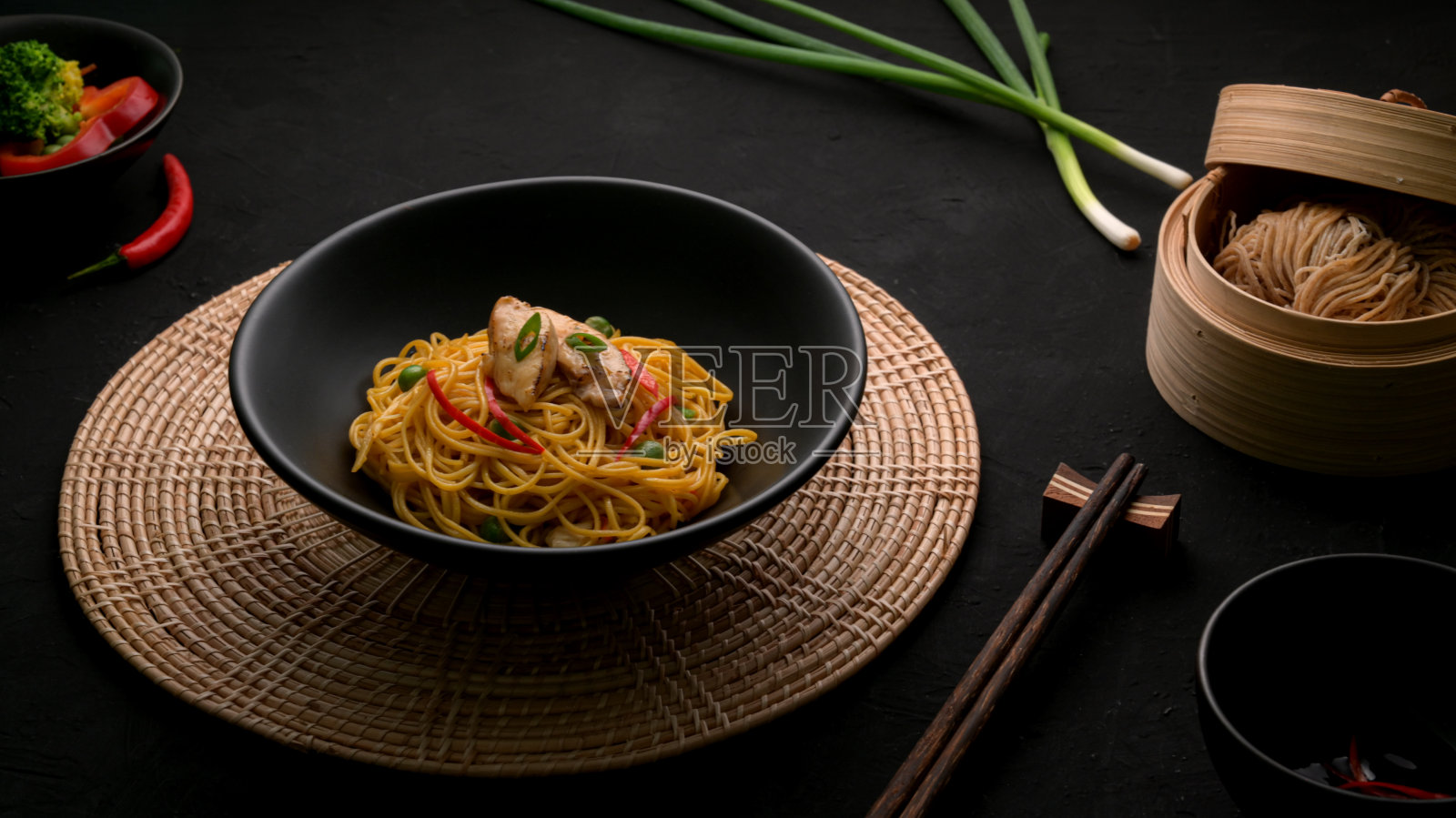 切好的四川面条，配上蔬菜、鸡肉和辣椒酱，盛在黑色的碗里照片摄影图片