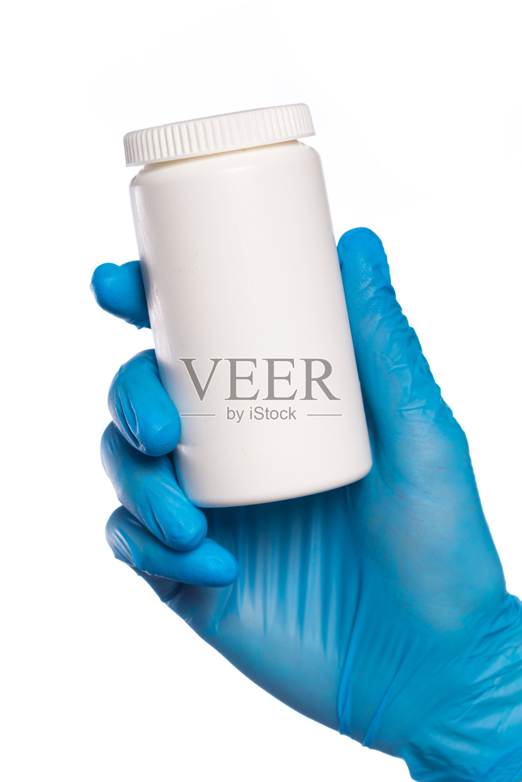 外科医生戴着蓝色医疗手套，手里拿着一个装有药丸的罐子。孤立在白色照片摄影图片