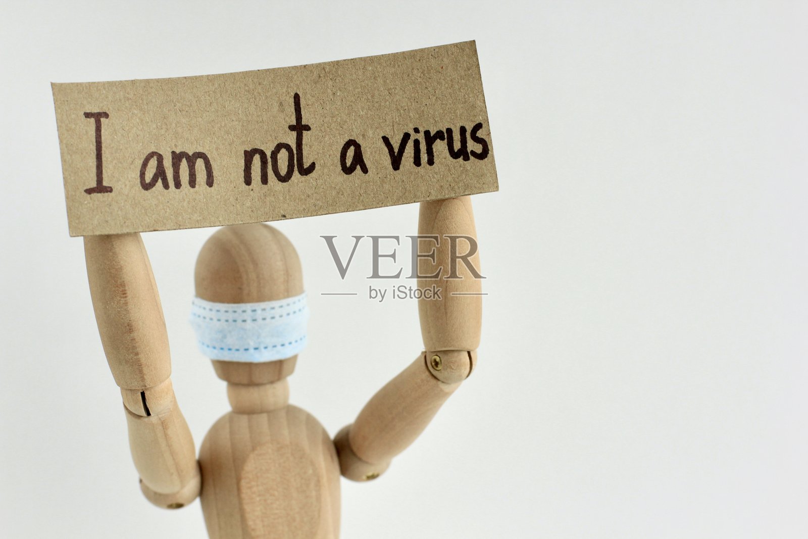 带着文字的纸板上写着“我不是木娃娃或带着医用面具的人体模型手中的病毒”。反种族主义、反仇外心理的概念，围绕新冠病毒或新冠肺炎的社会状况照片摄影图片