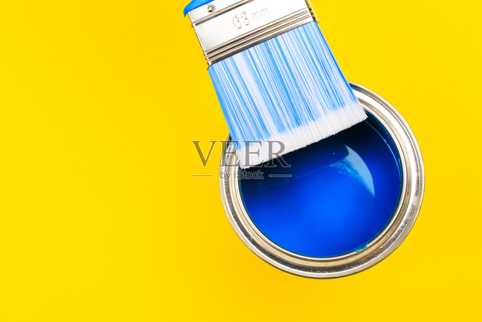 手持画笔在开罐油漆上黄色背景。改造的概念照片摄影图片