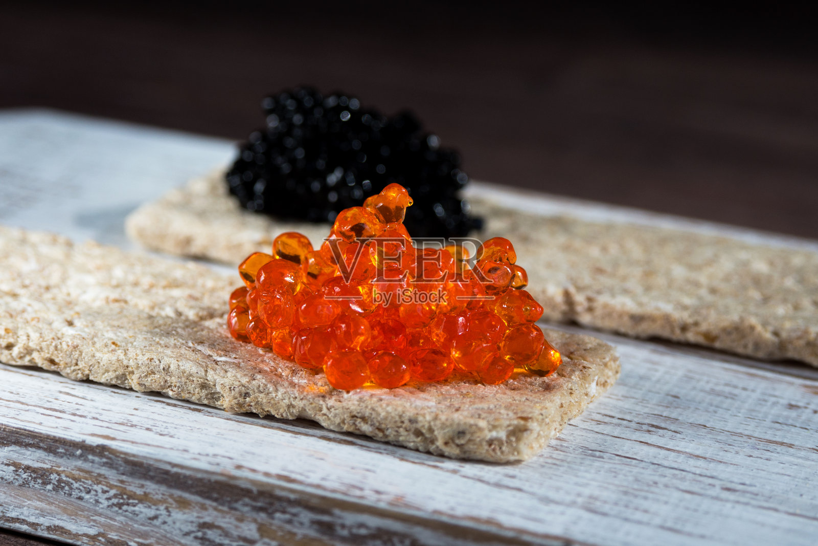 用海带海藻做成的红色和黑色素食鱼子酱放在脆饼上。对健康饮食有价值和健康的产品。照片摄影图片