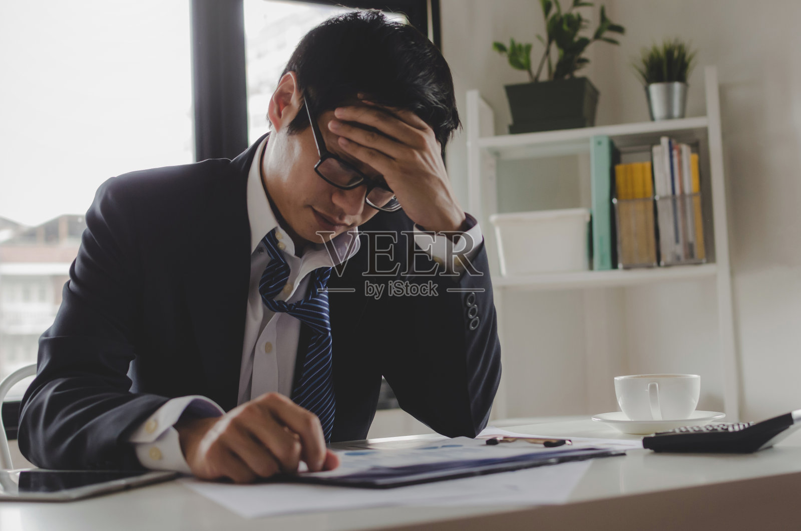 疲惫沮丧的亚洲年轻员工在家居办公室处理财务报表，面临财务危机和营销难题照片摄影图片