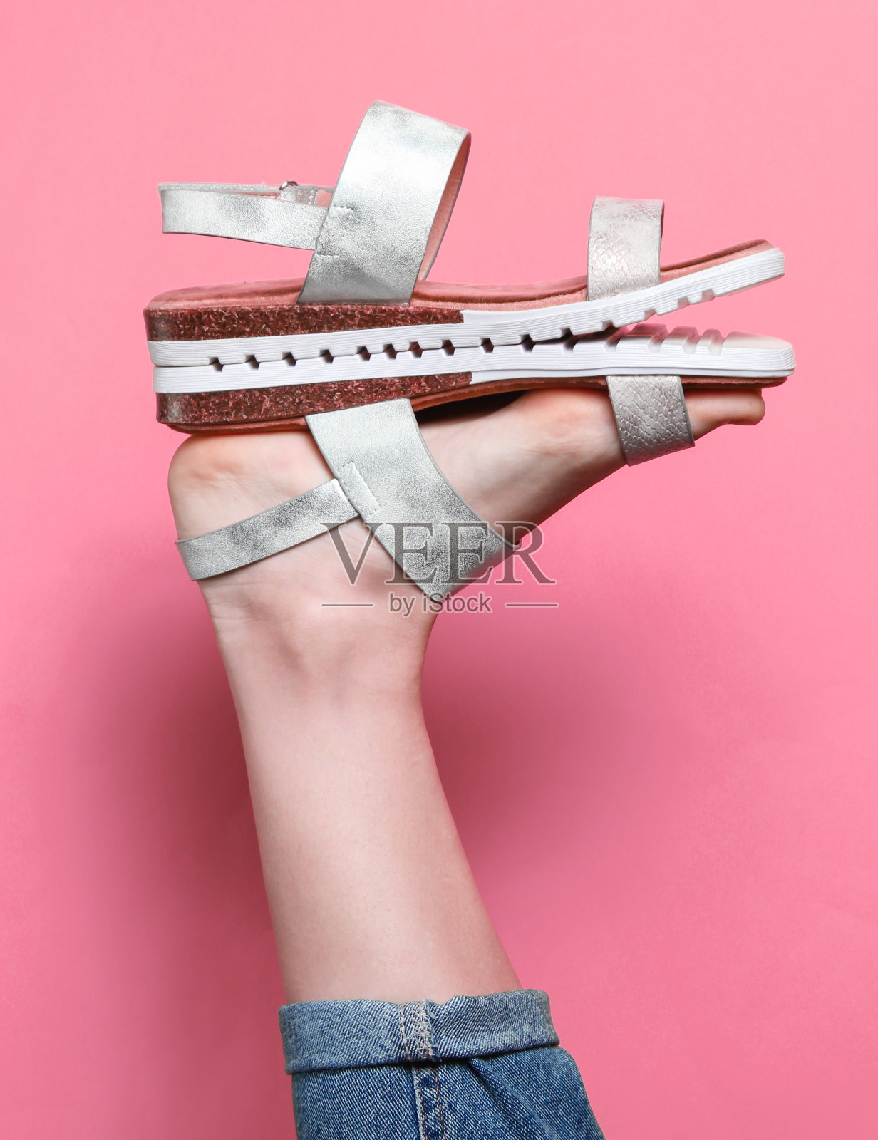 创意时装拍摄。时尚的女性凉鞋在提高女性腿后跟在粉红色的背景。照片摄影图片