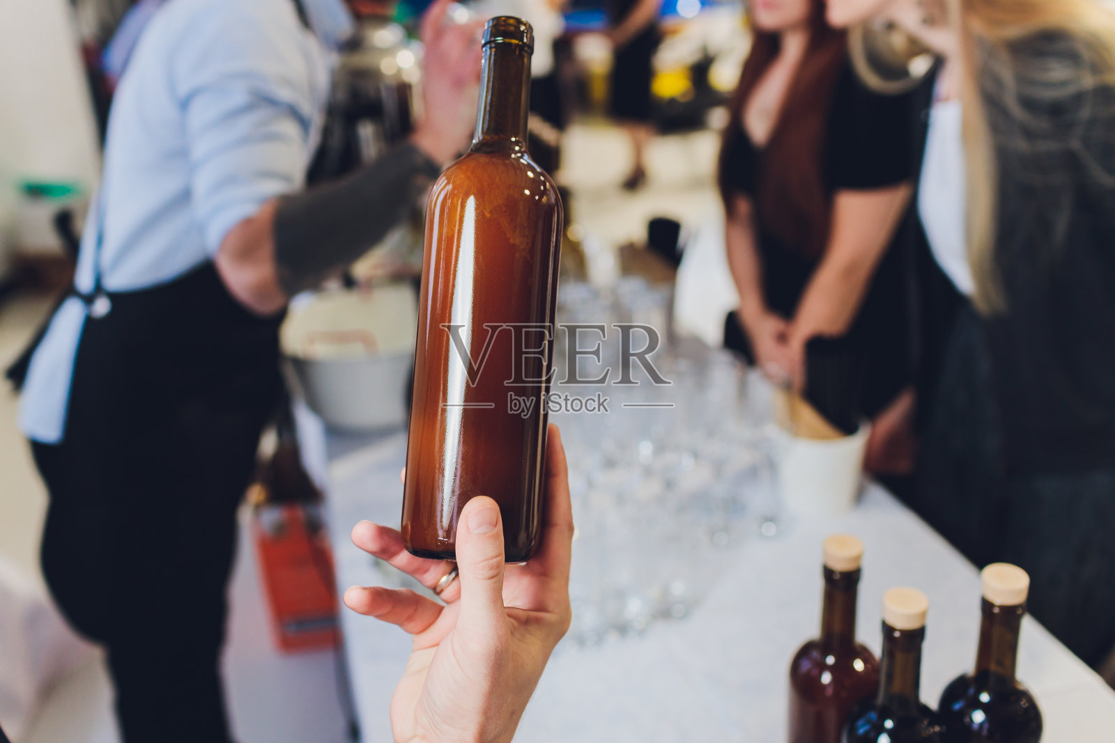 这个人手里拿着一个红酒瓶子。照片摄影图片