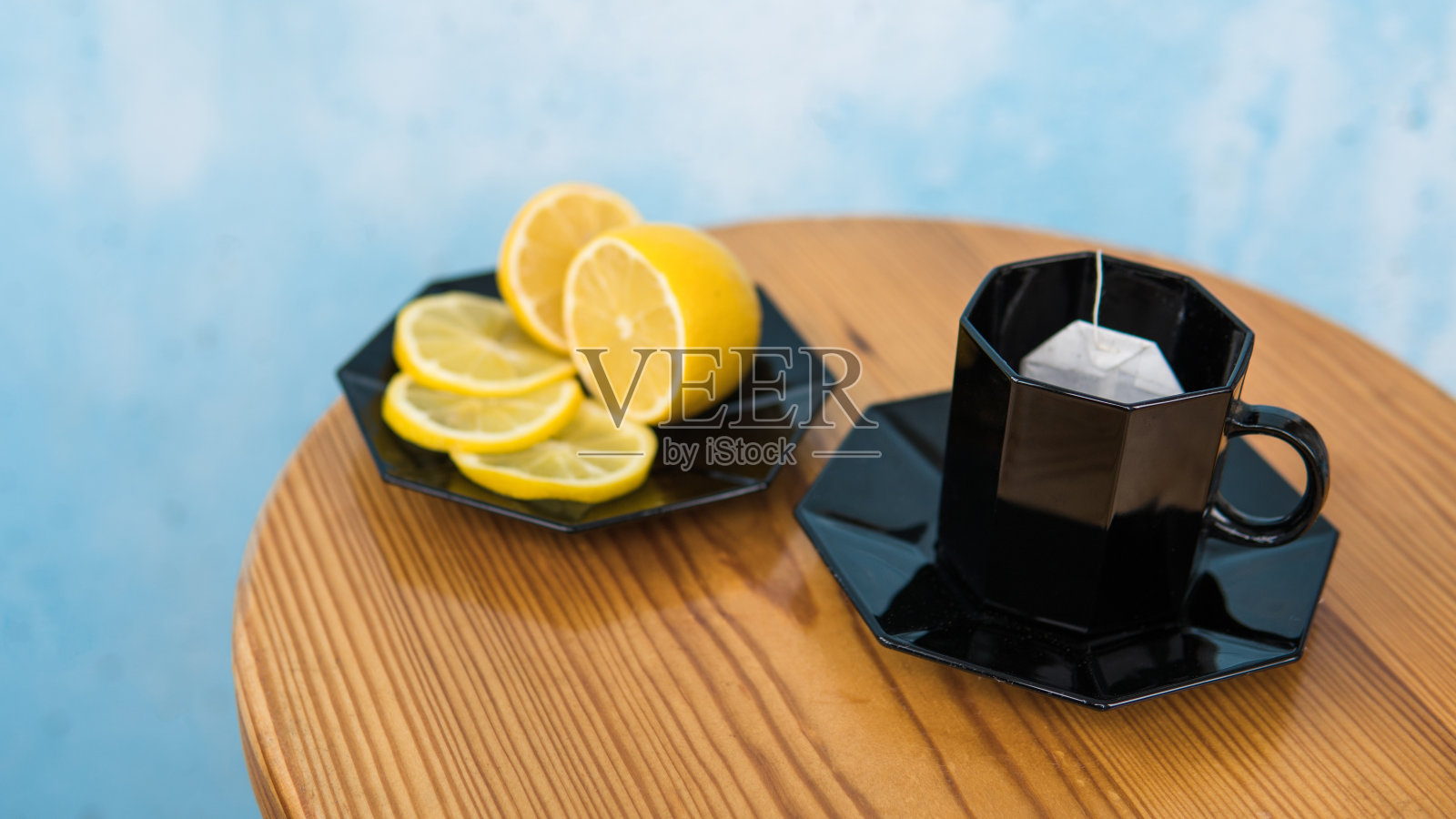 茶包，黑色杯子，浅棕色桌子，蓝色水泥背景照片摄影图片