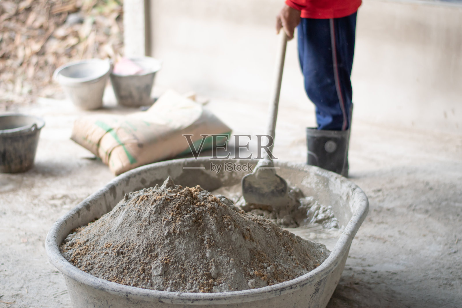 水池里的水泥和沙子的特写。建筑工人正在搅拌水泥。照片摄影图片
