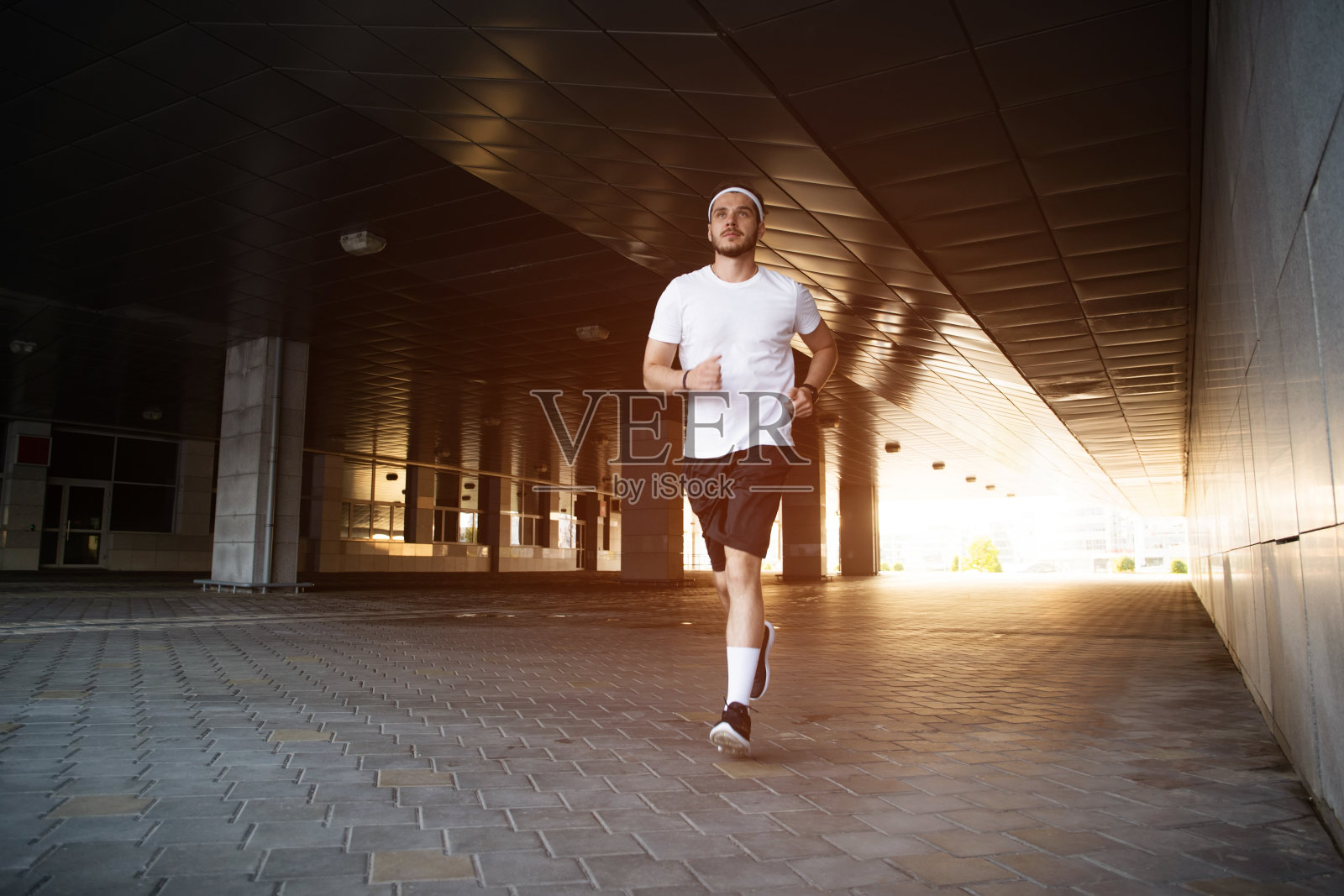 日落时分在城市跑步的健壮男人。健身、锻炼、运动、生活方式概念照片摄影图片