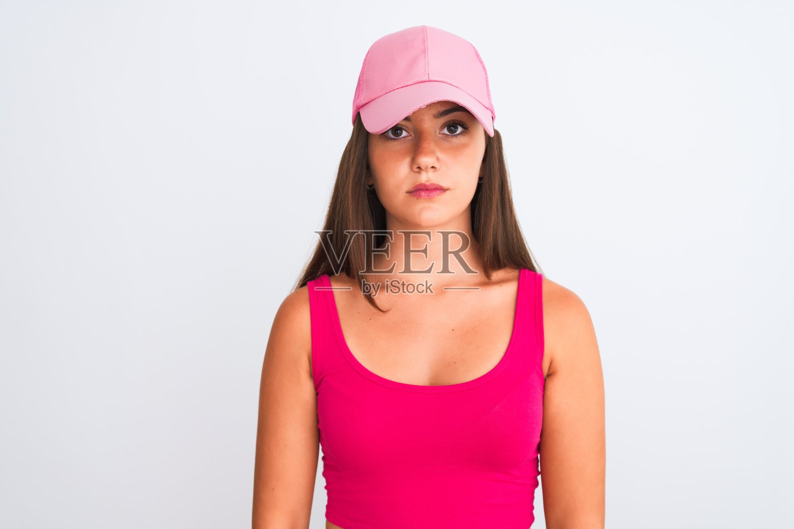 年轻漂亮的女孩穿着粉色休闲T恤和帽子，面无表情，直视镜头照片摄影图片