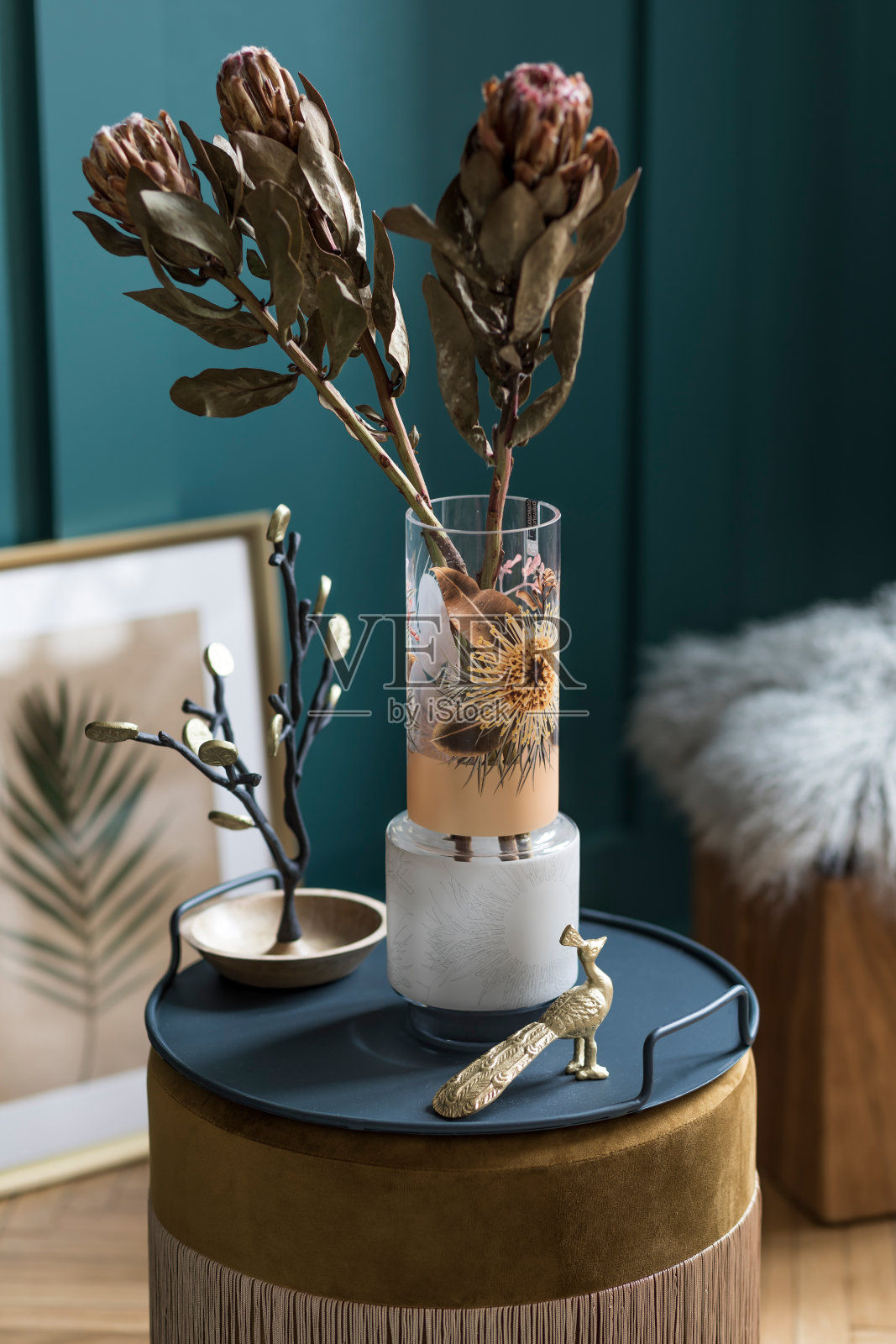 时尚和花卉组成的美丽的花在现代花瓶上天鹅绒蒲团与优雅的配件和家具。客厅的花朵概念。绿色的墙。室内设计模板照片摄影图片