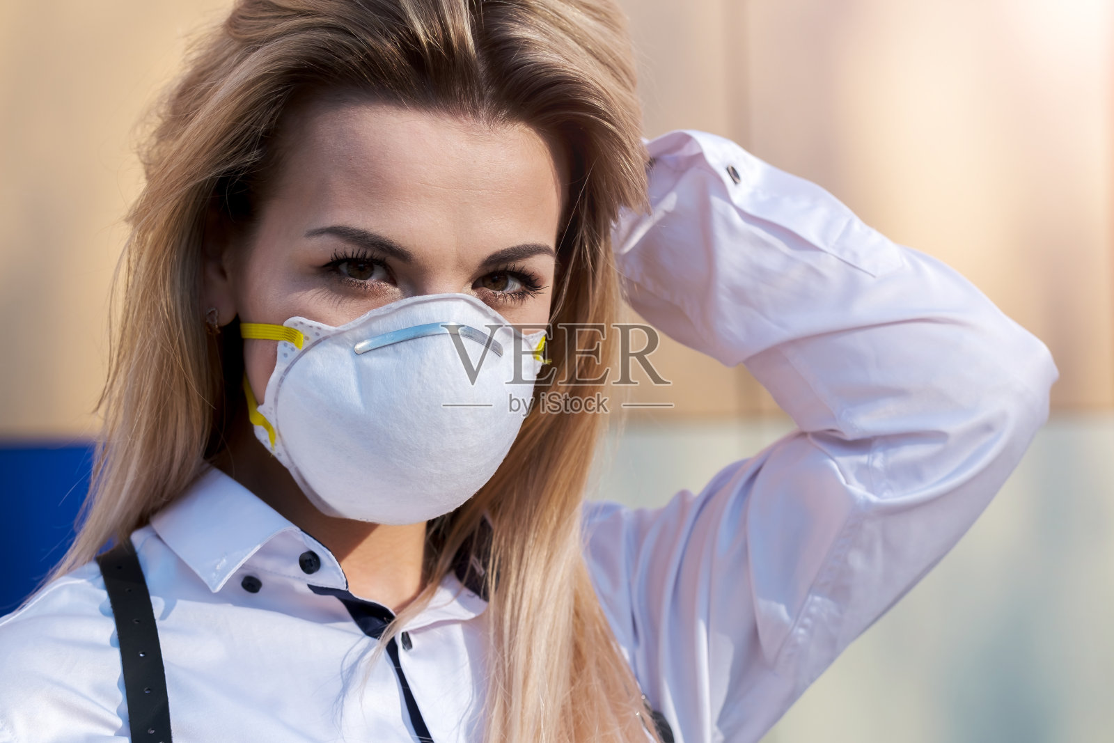 年轻漂亮的金发白种女孩戴着防护面具站在户外，照片摄影图片