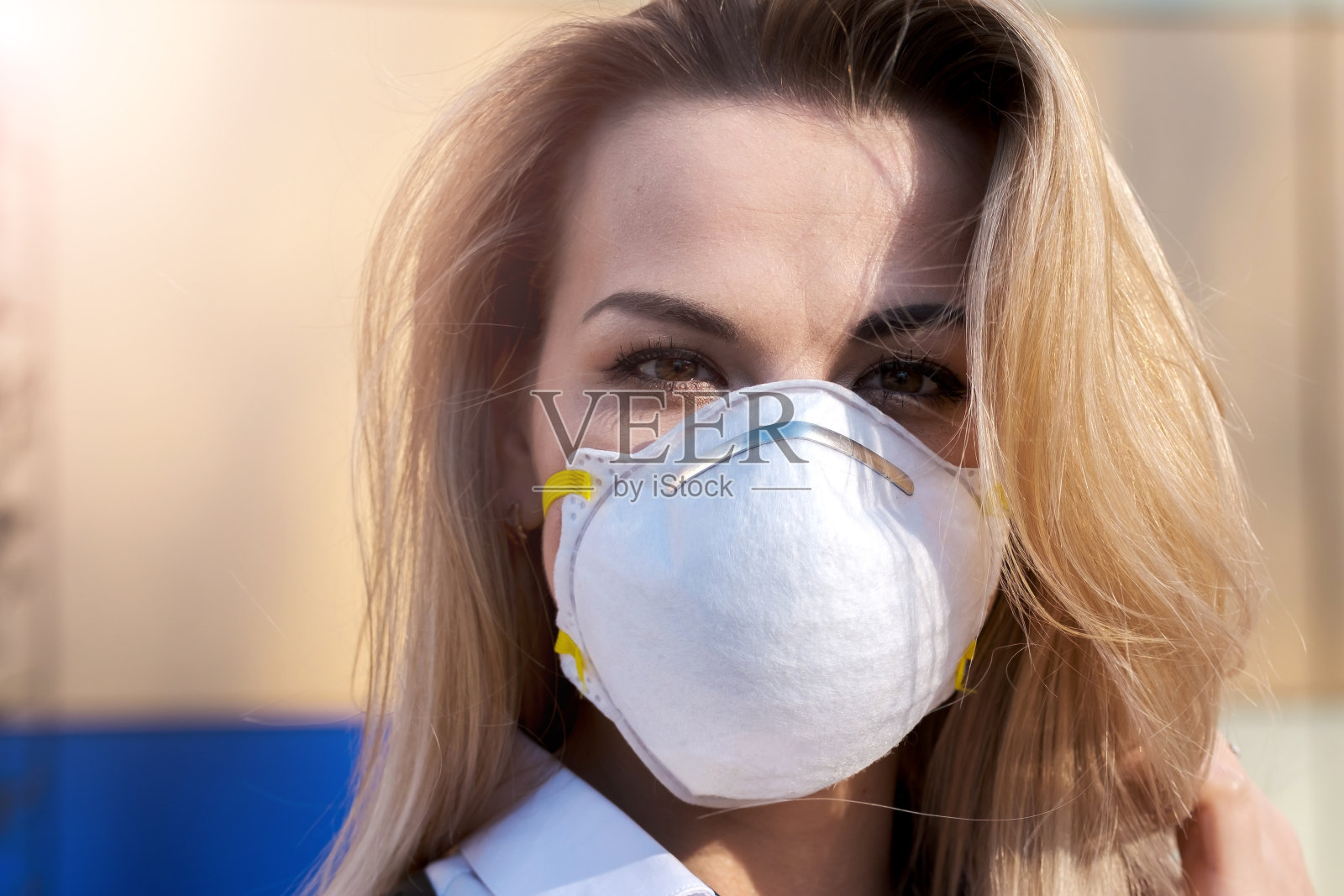 年轻漂亮的金发白种女人戴着防护面具站在户外，照片摄影图片