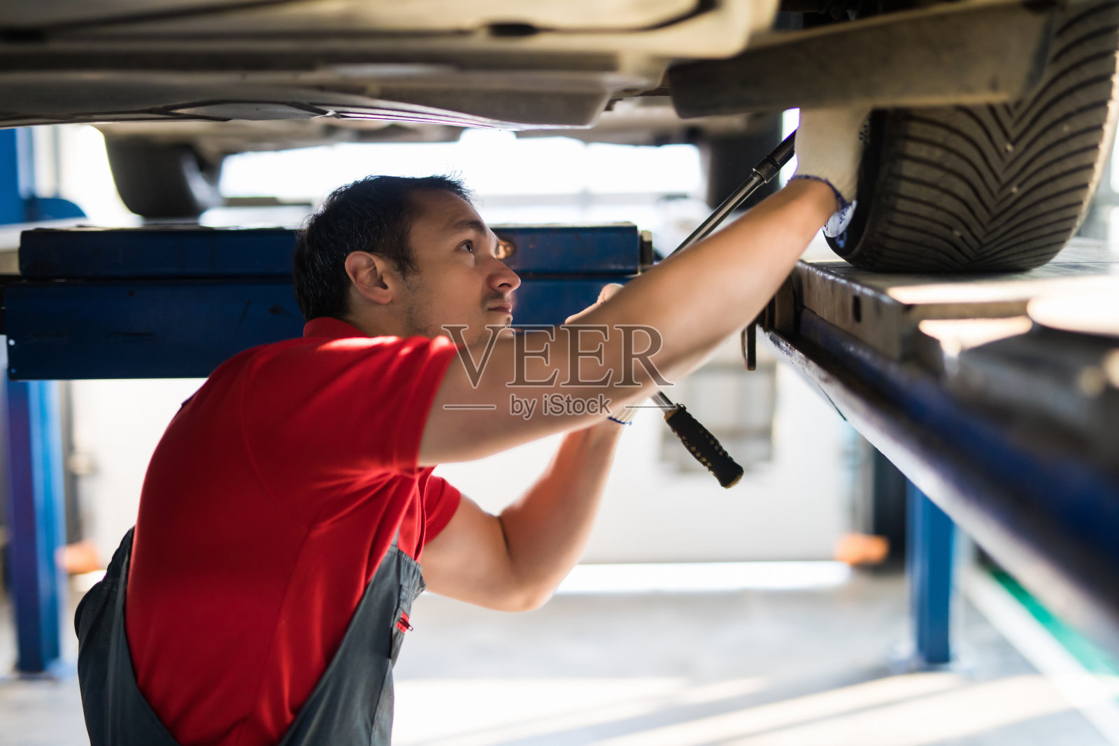 汽车修理工用扳手紧固汽车悬架部件照片摄影图片