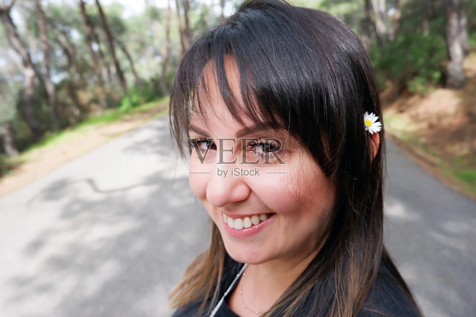 耳朵上戴着雏菊的30多岁微笑白人女子肖像照片摄影图片