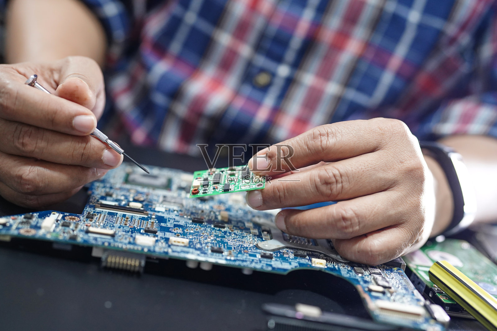技术员用烙铁修理硬盘内部。集成电路。数据、硬件、电子垃圾和技术的概念。照片摄影图片