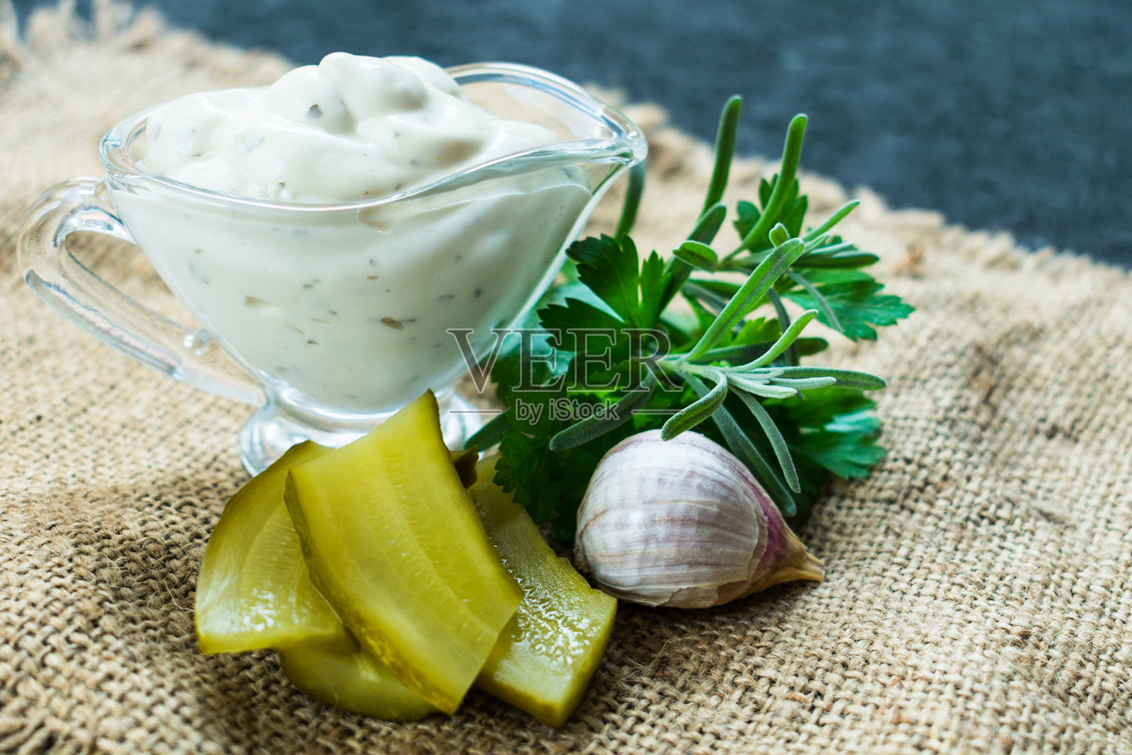 塔塔酱装在玻璃盘子里，配料在黑色的背景上。照片摄影图片