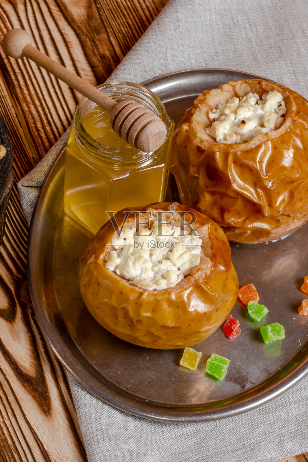 健康食品。木桌上的一个黑色烤盘里放着烤过的苹果，上面放着白软干酪和坚果照片摄影图片