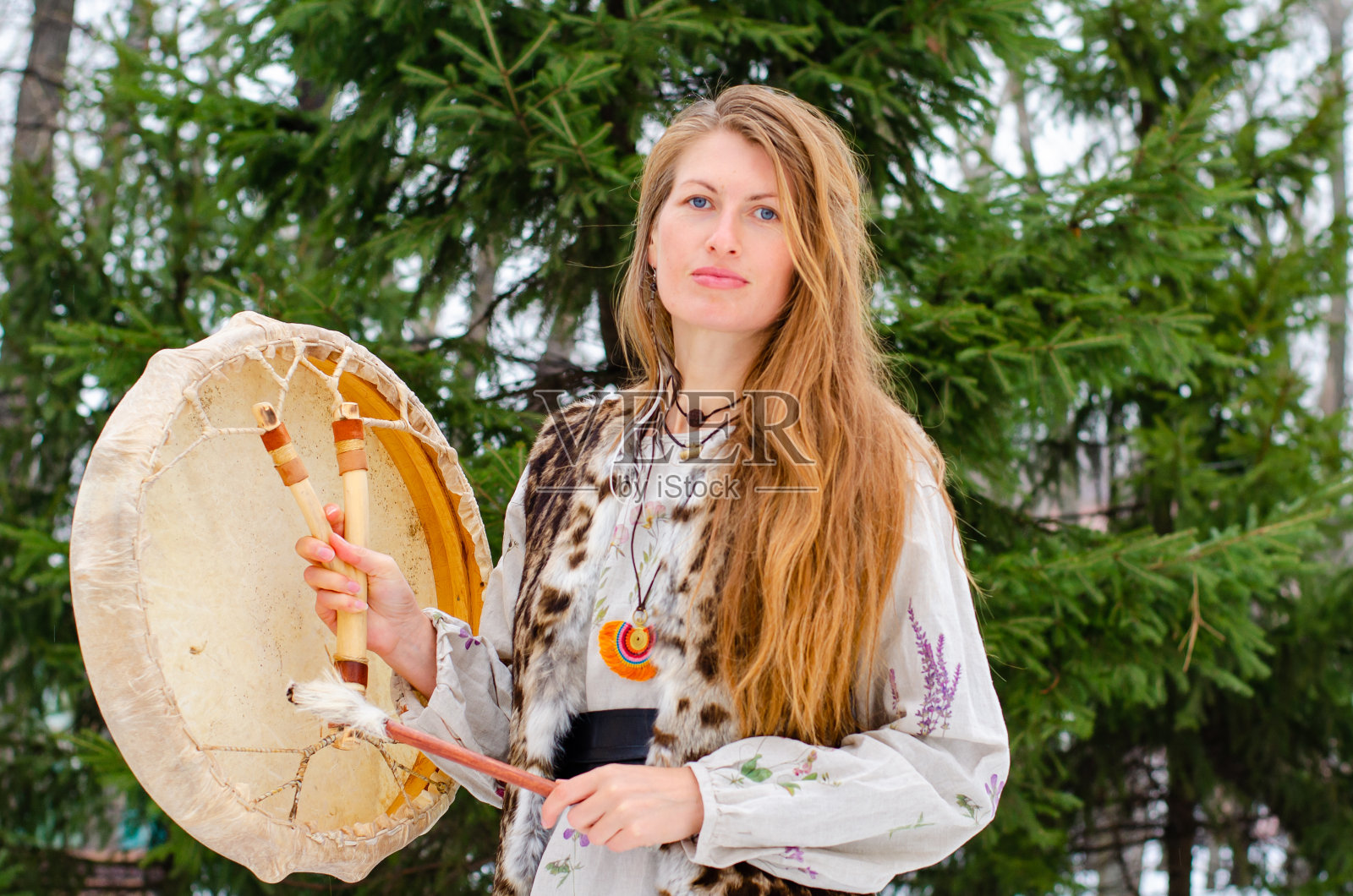 穿传统服饰的女子在森林里敲击萨满鼓照片摄影图片
