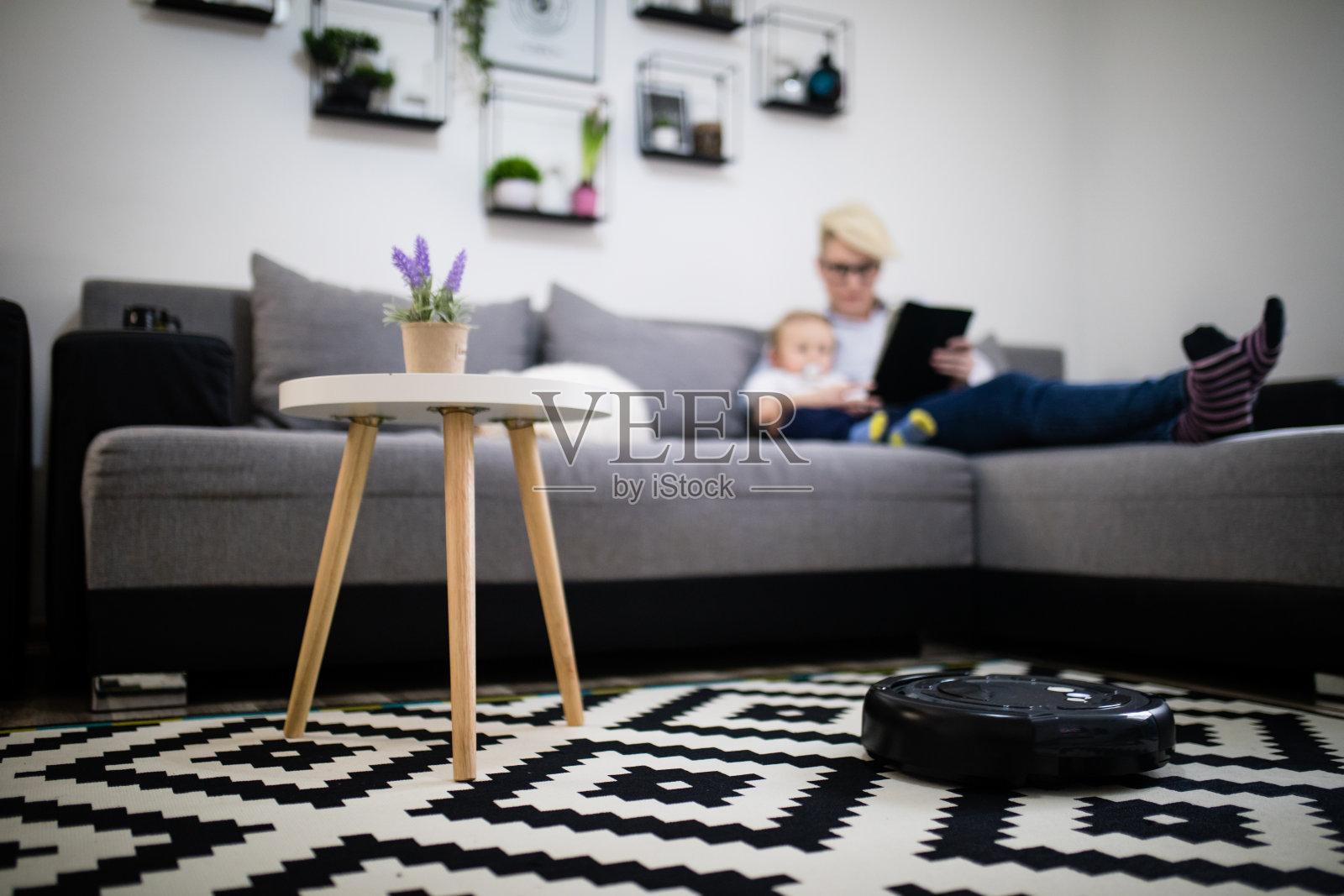 女人和男孩在家使用平板电脑，机器人吸尘器正在清洁地面。现代生活方式概念。照片摄影图片