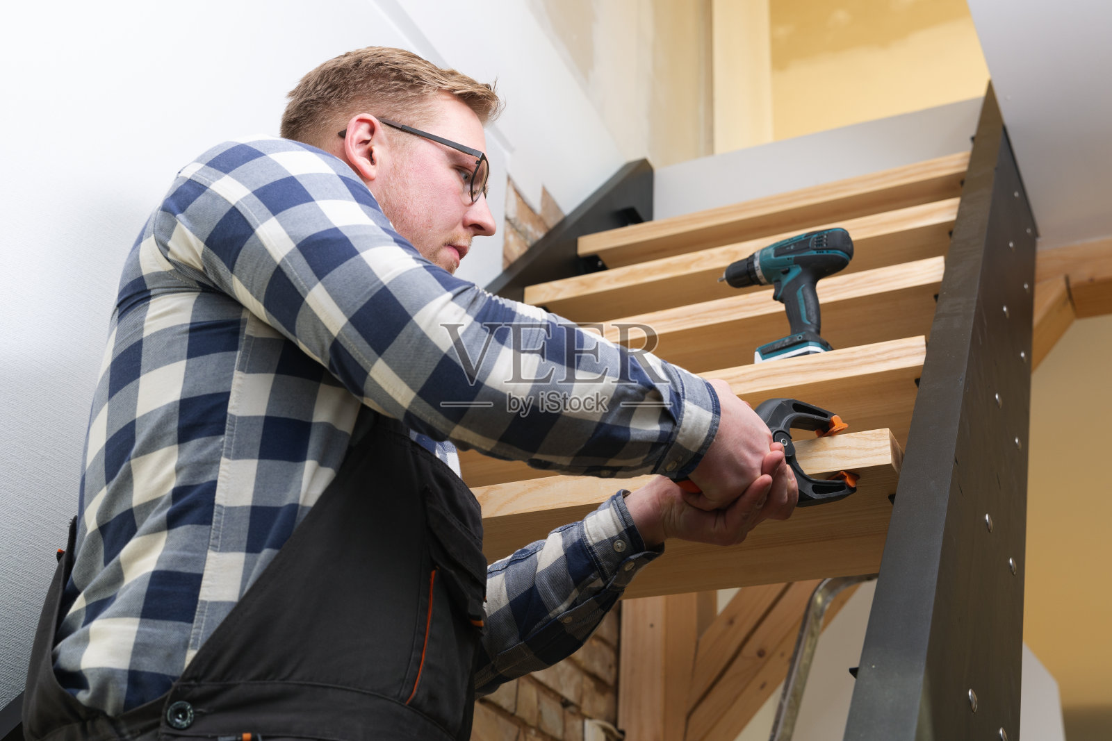 自然光下手脚架上的房屋装修工人照片摄影图片