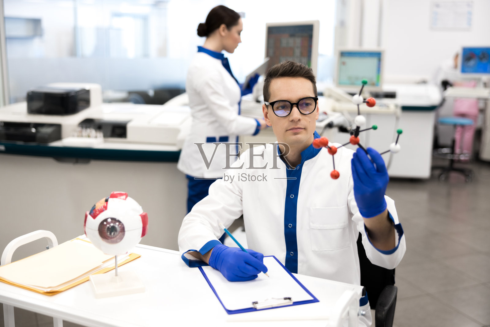 身穿实验服的研究科学家观察分子模型照片摄影图片