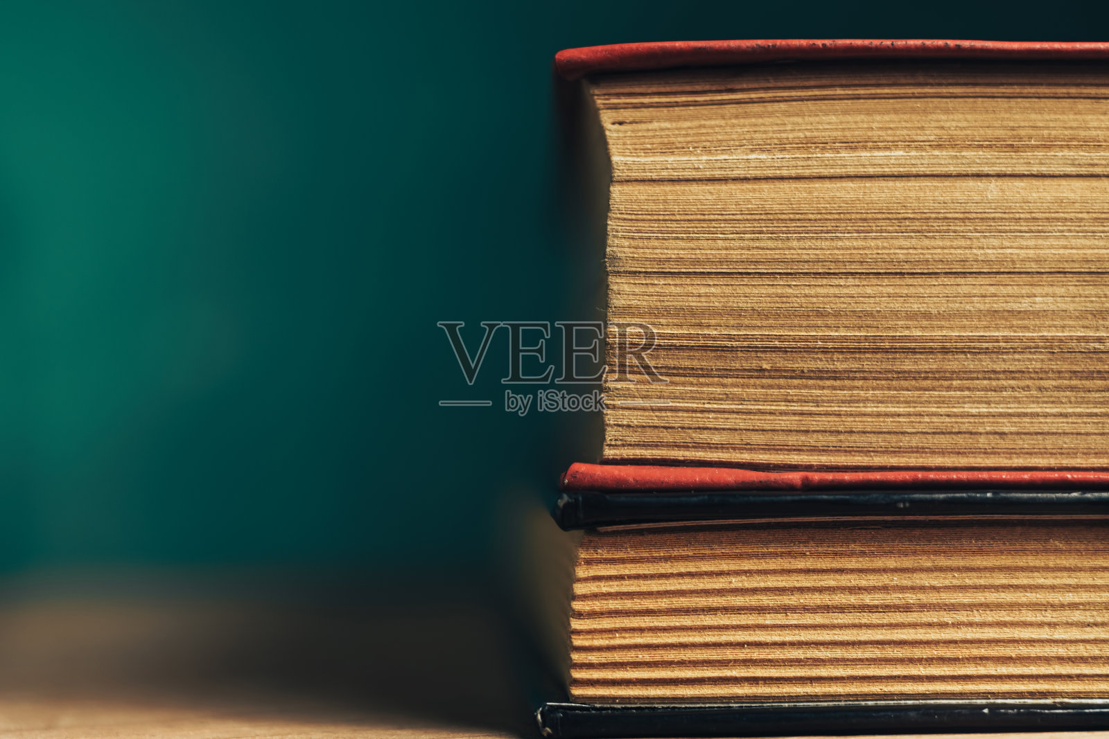 近距离观看美丽的古书。图案背景设计。书放在红色的木桌和绿色的墙壁上。照片摄影图片