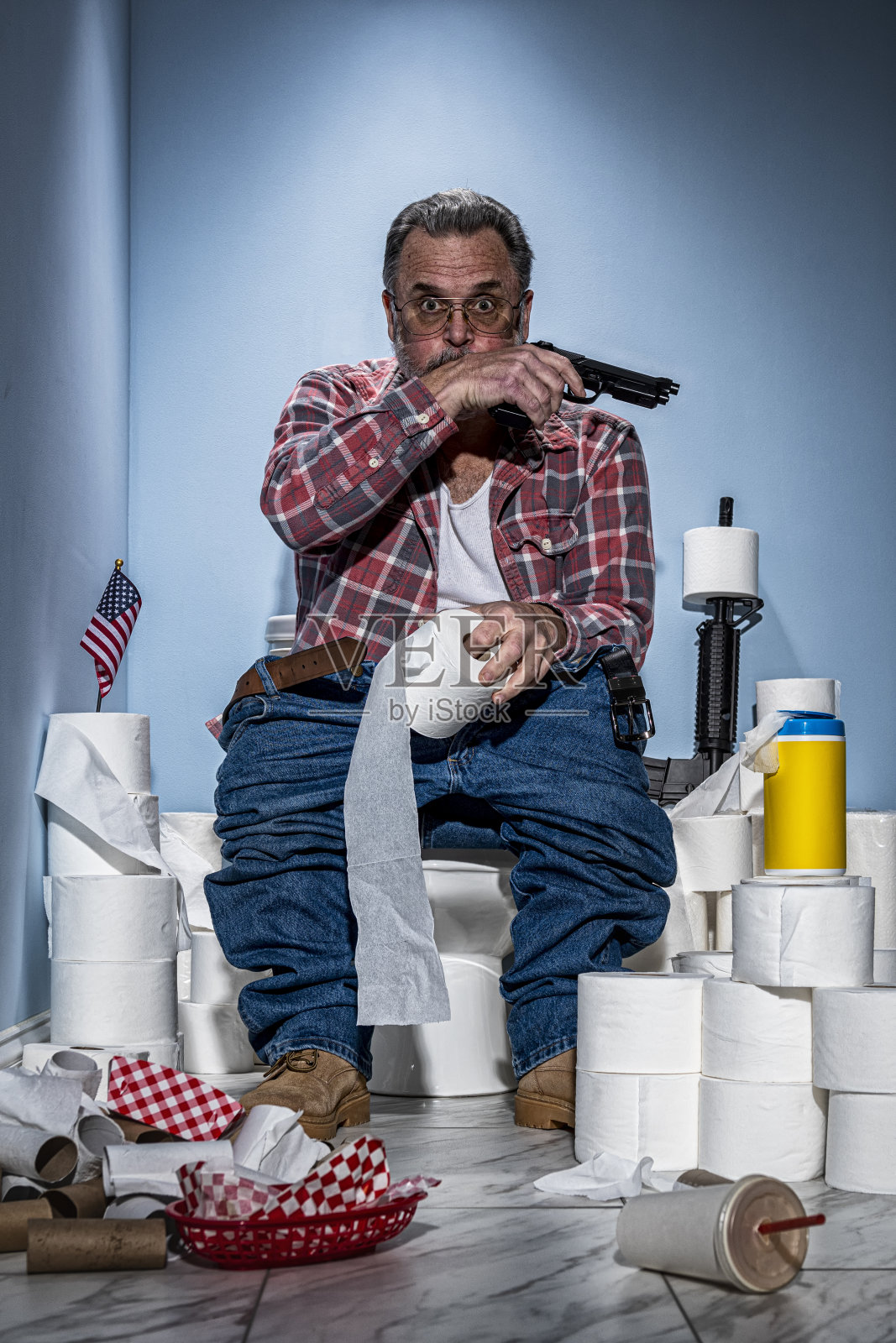 消化不良的男子坐在马桶上，用手枪守卫着他的卫生纸照片摄影图片