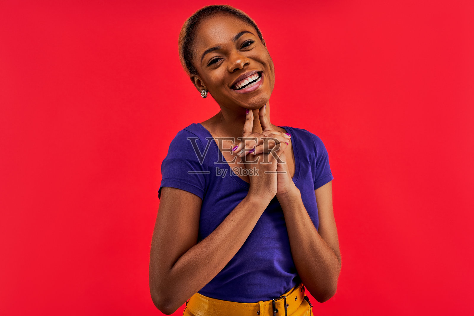 戴耳环、穿蓝色T恤对着镜头微笑的女人，情感概念照片摄影图片