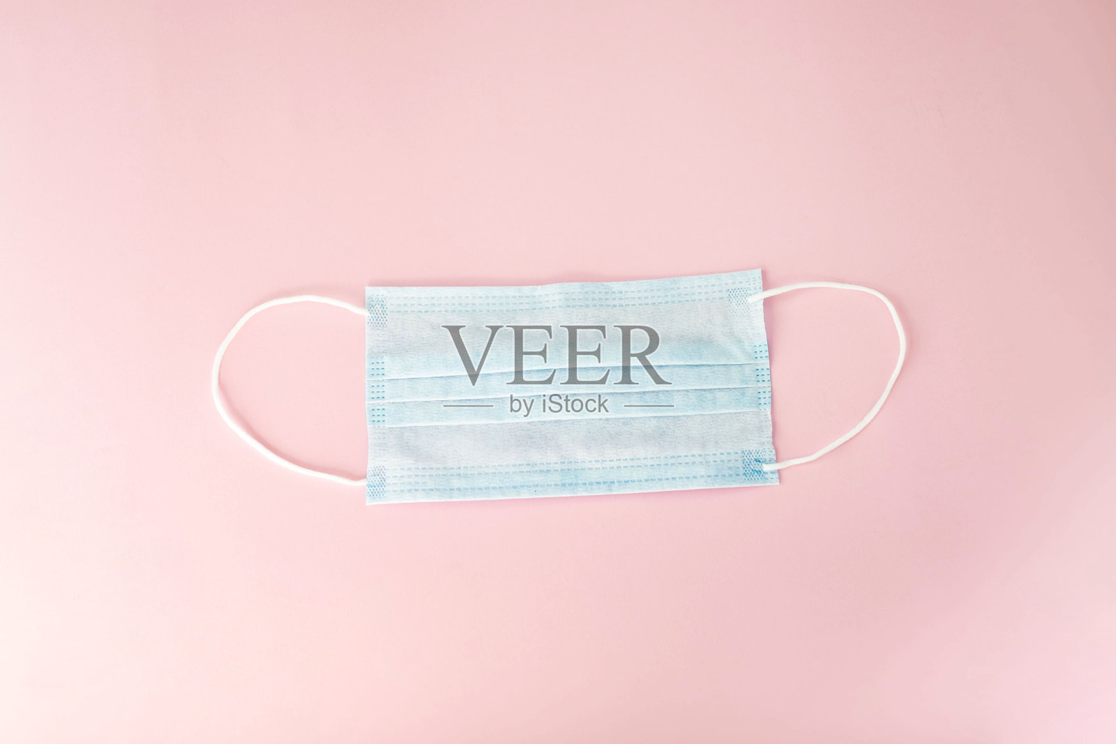 预防流感和其他疾病的蓝色医用口罩，粉红色背景。预防病毒和流行病的传播。外科防毒面具照片摄影图片