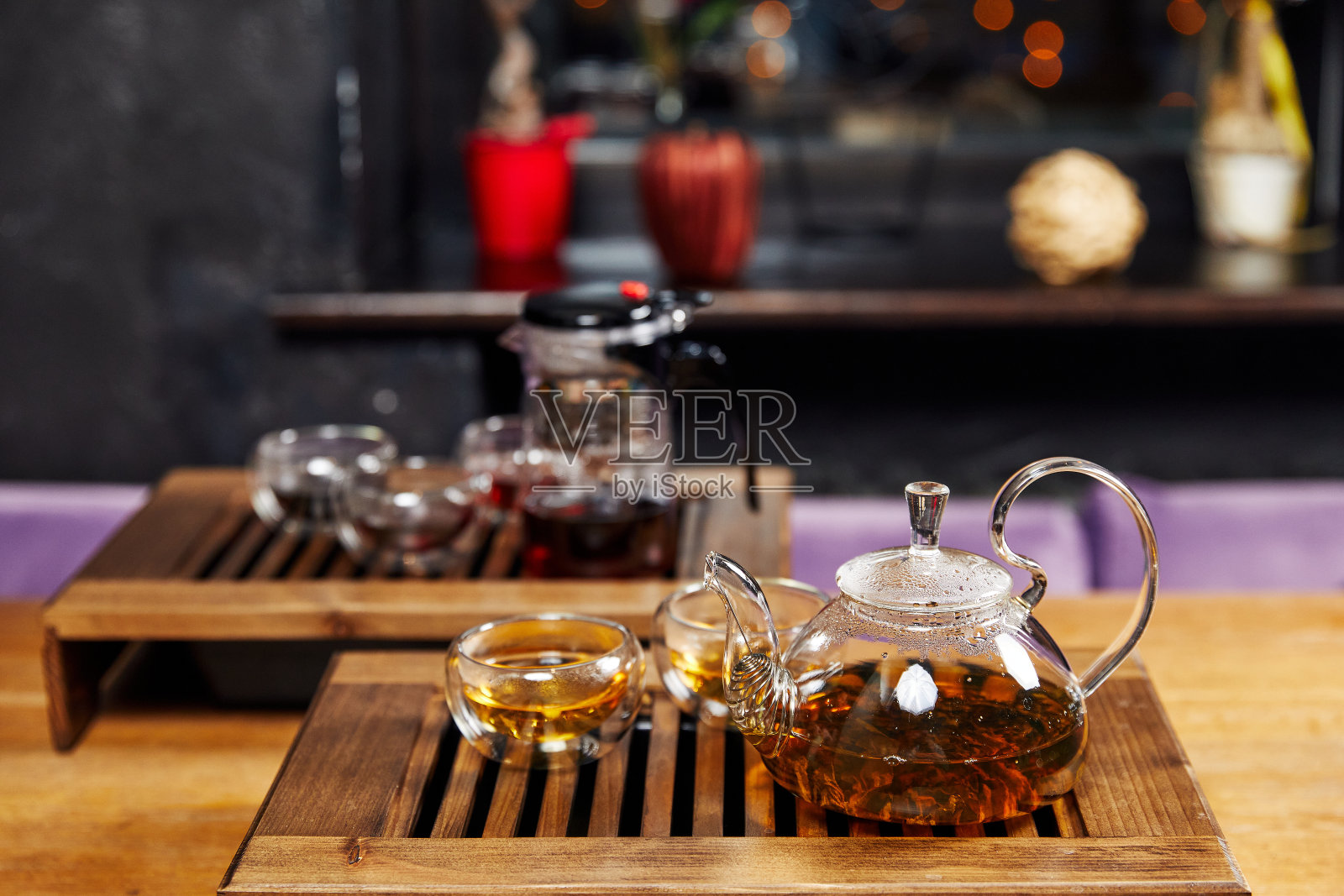 装有茶叶和杯子的玻璃茶壶放在一个木架上照片摄影图片