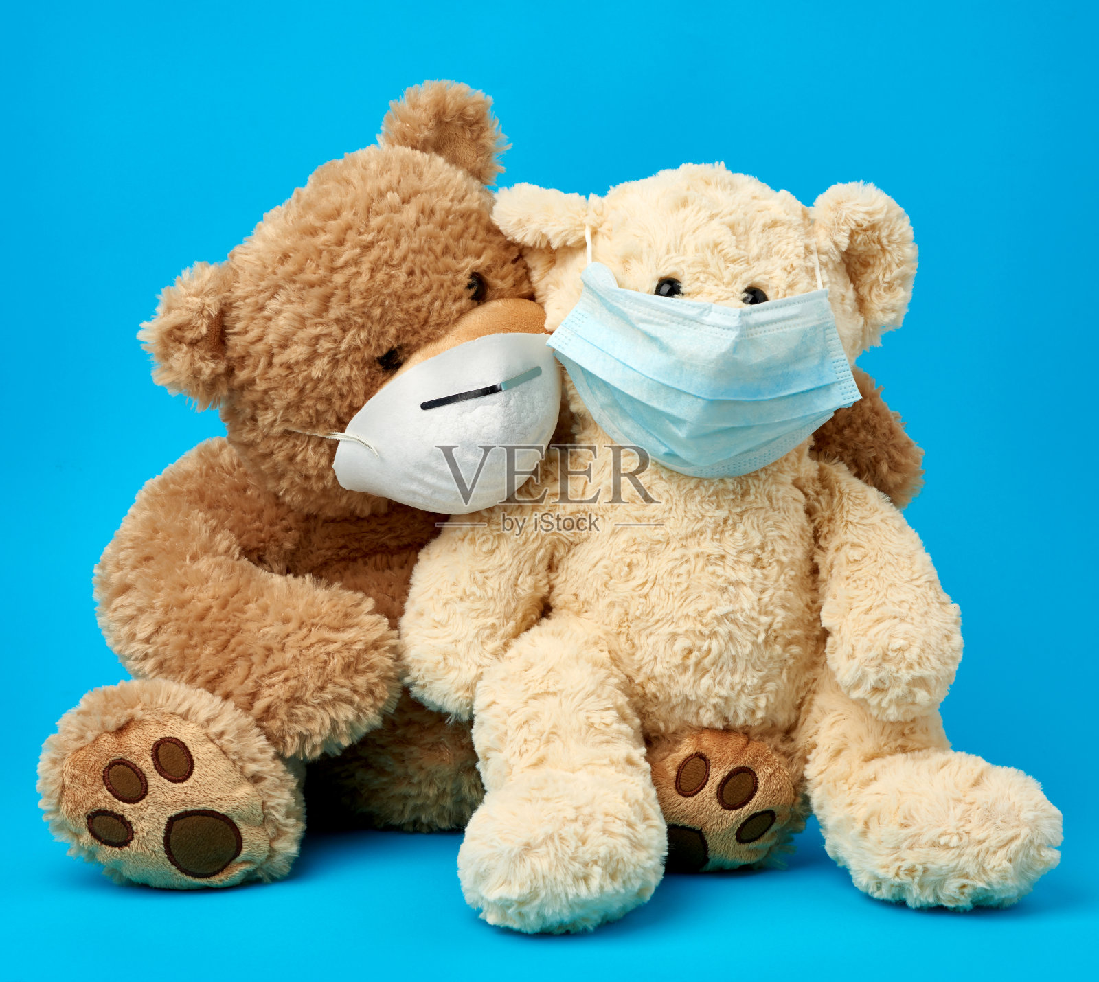 蓝色背景上的大泰迪熊戴着医用口罩照片摄影图片