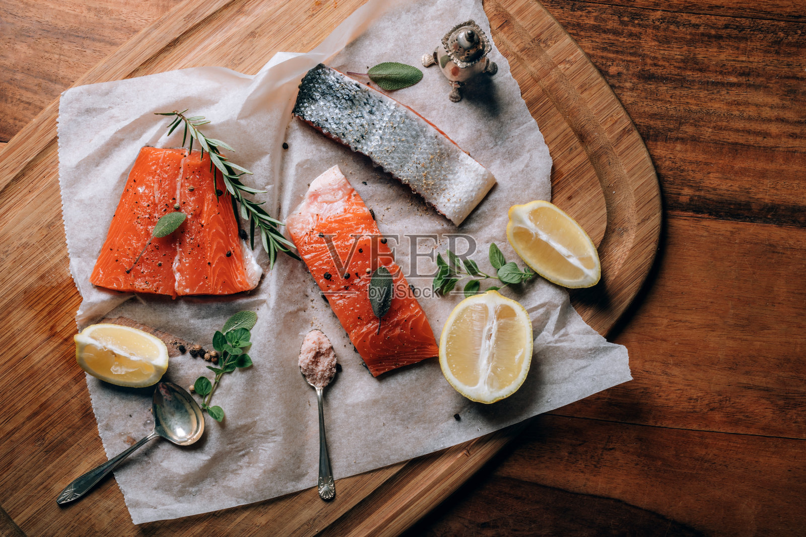 切板上的纸上印着新鲜的生鲑鱼，配上柠檬、香草和香料照片摄影图片