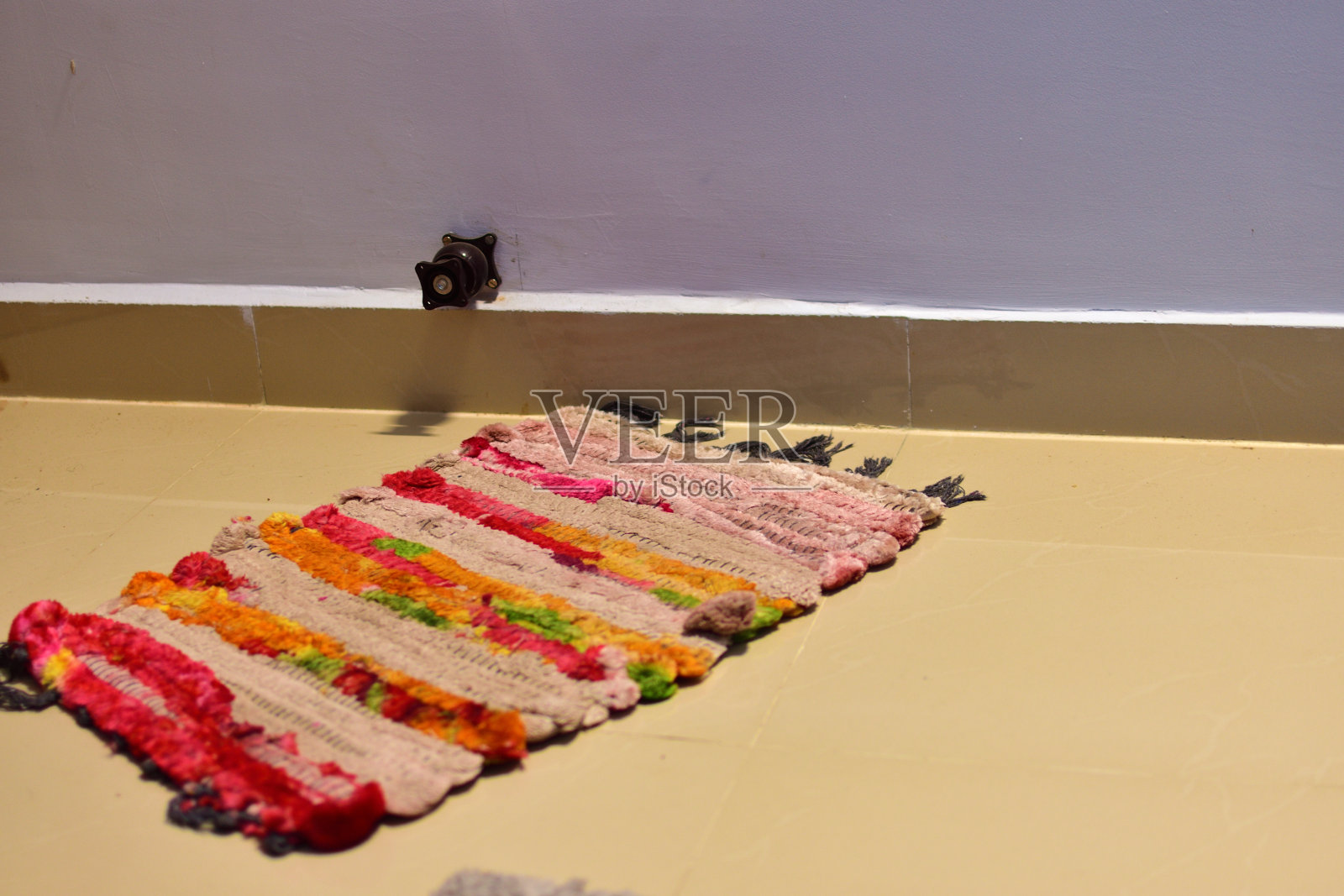 旧的多色酒店门垫在石头地板上。房间门口的节日欢迎垫。照片摄影图片