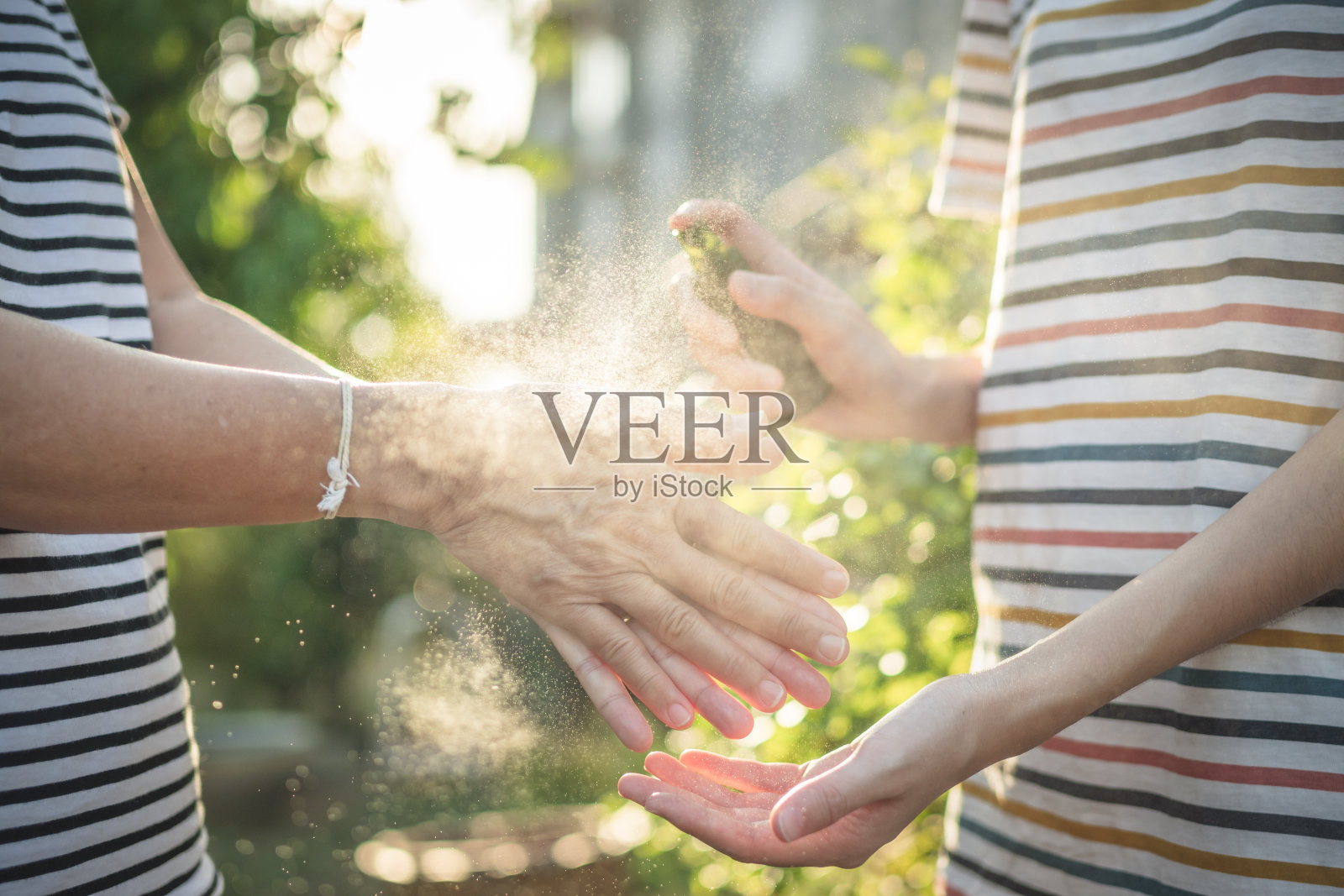 亚洲人戴口罩，手喷酒精消毒剂，防止新冠病毒传播照片摄影图片