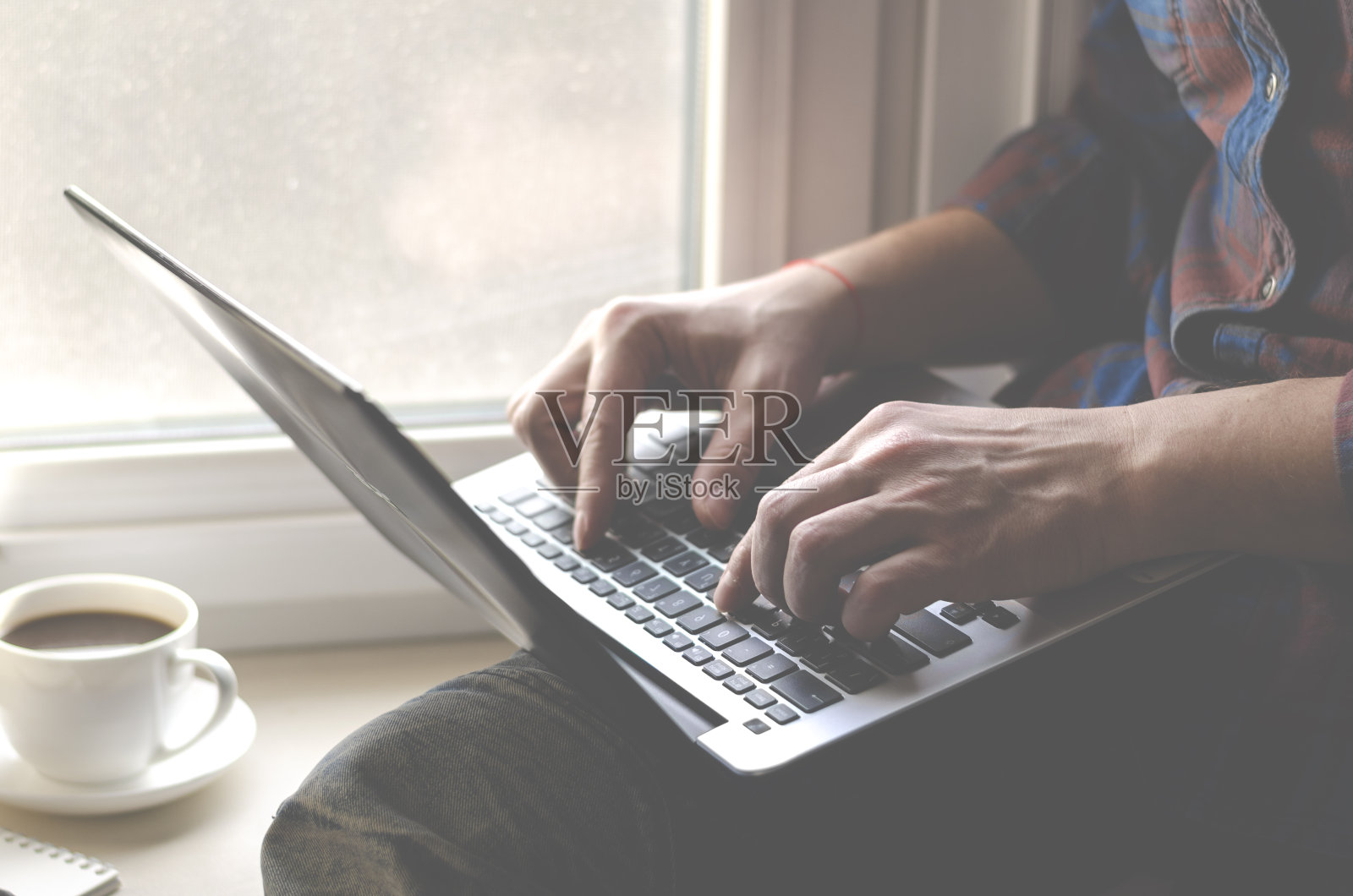 在家庭办公室使用笔记本电脑的男人。男性的手在键盘上打字照片摄影图片