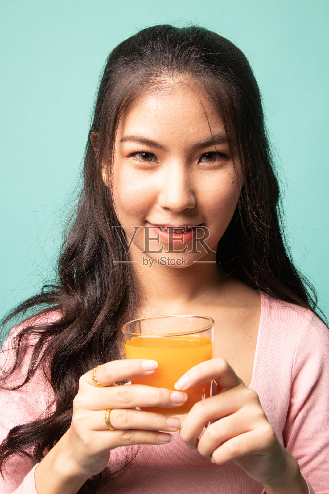 年轻的亚洲妇女喝橙汁。照片摄影图片