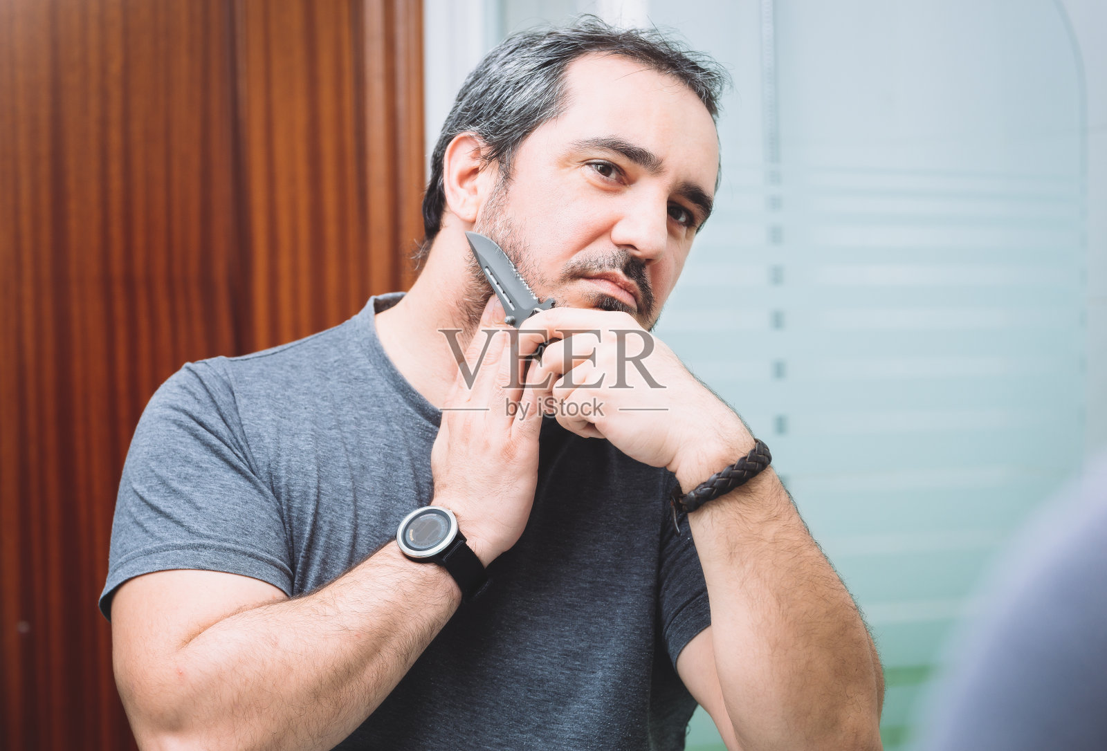 40多岁的男人用锋利的猎刀刮胡子照片摄影图片