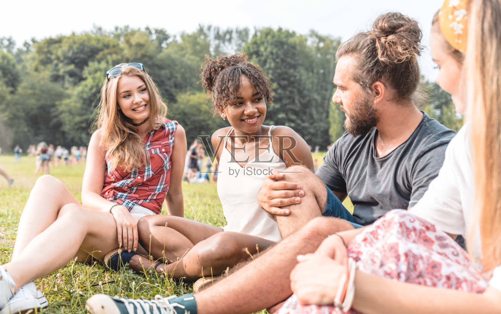 朋友们坐在户外公园的草地上照片摄影图片