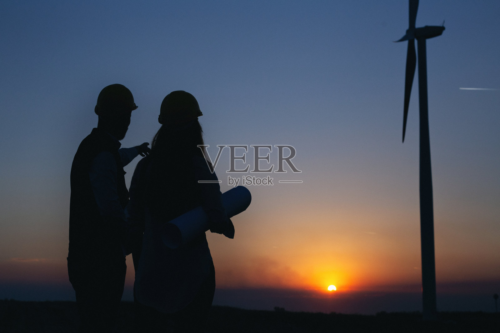 年轻的电气工程师站在风车前照片摄影图片