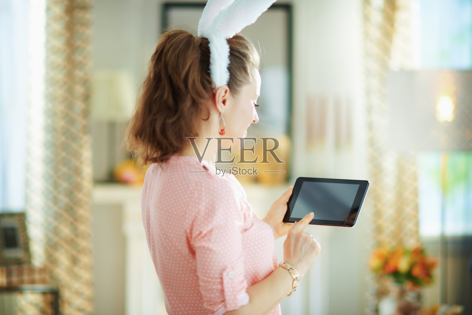 在阳光明媚的春日，身处现代客厅中使用平板电脑的女人照片摄影图片