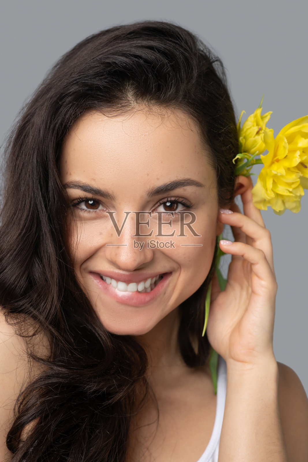 漂亮的黑发女孩，头发上戴着一朵花，笑容可掬照片摄影图片