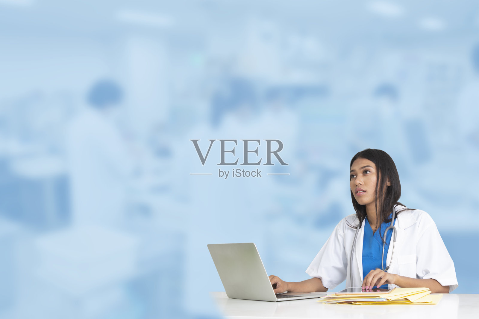 在蓝色模糊医学实验室背景前工作的女医生照片摄影图片