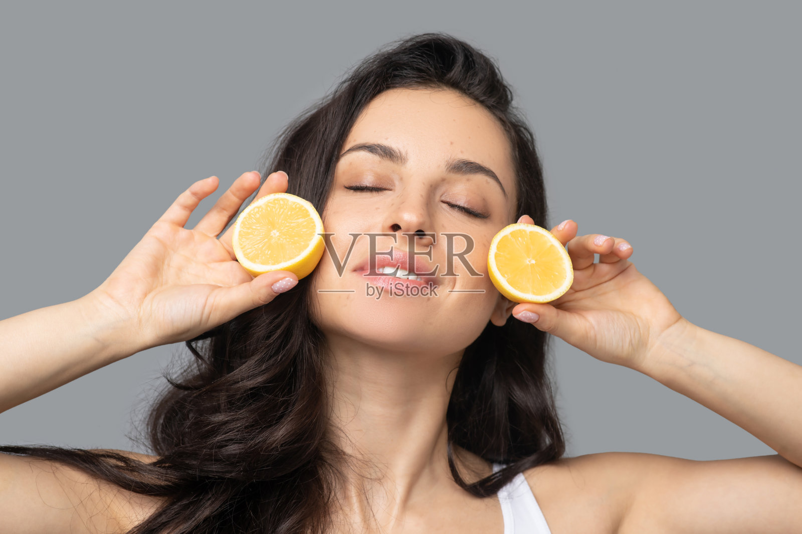 漂亮的黑头发女孩，手里拿着橙黄色的两半照片摄影图片